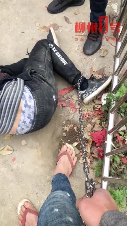 偷狗被抓！柳州一男人被铁链拴在栏杆上世人喊打，有人猛踹其屁股